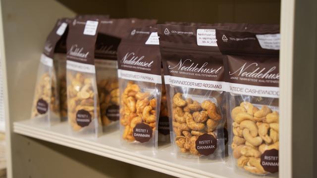 Forskellige poser med nødder fra Nøddehuset står på en hylde